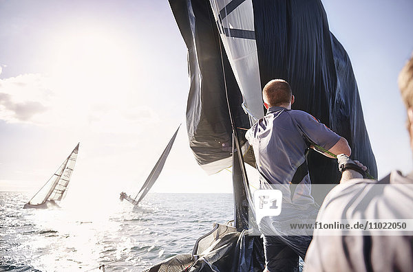 Mann segelt auf dem sonnigen Meer