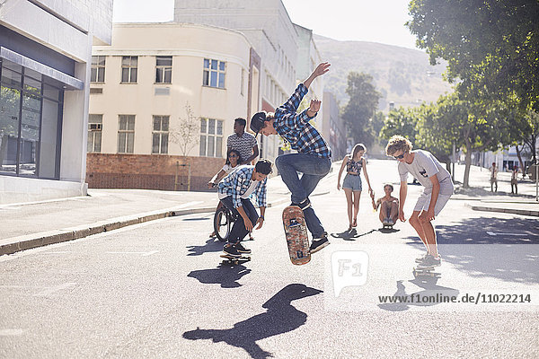 Teenager-Freunde skateboarden auf der sonnigen Stadtstraße