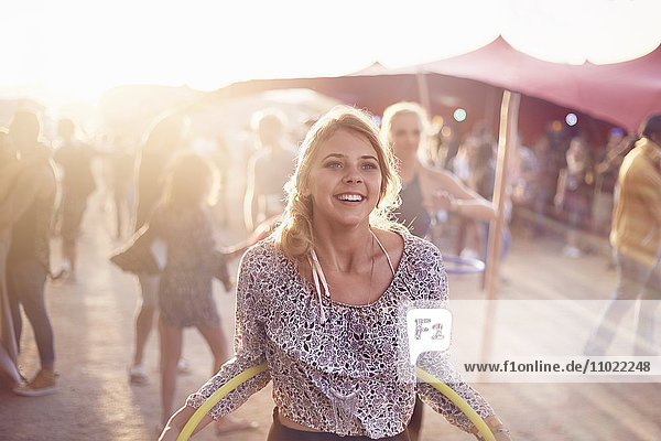 Lächelnde junge Frau mit Kunststoffreifen beim Musikfestival