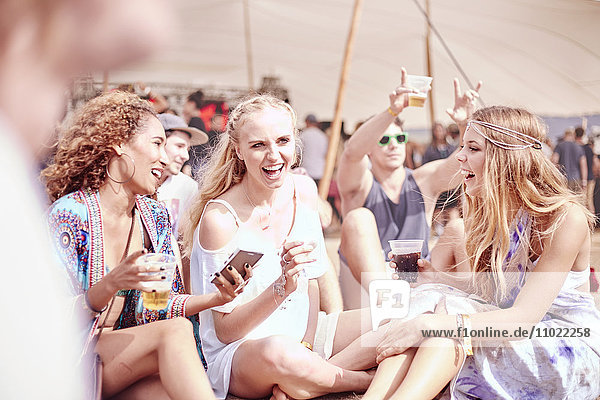 Junge Frauen  die auf einem sonnigen Musikfestival trinken