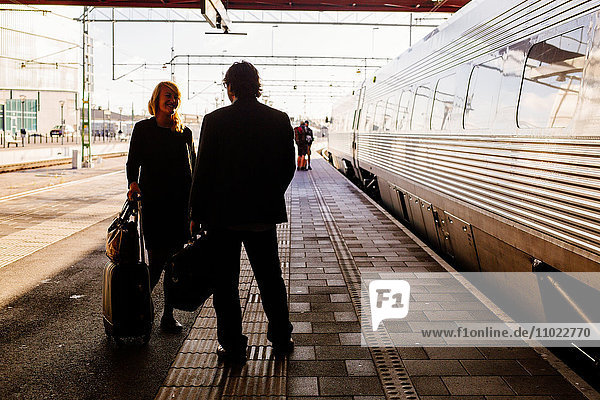 Full length of business people with discussing at railroad station
