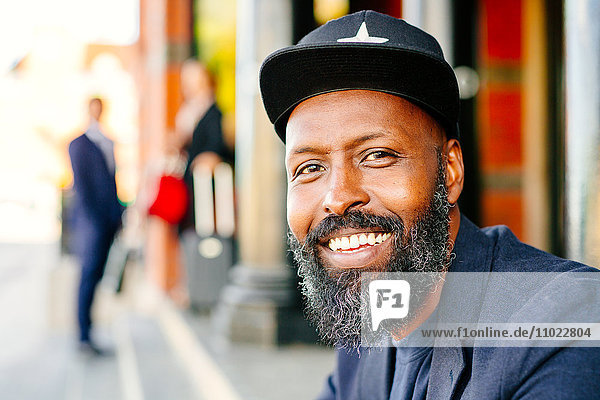 Portrait of happy businessman sitting outside railroad station