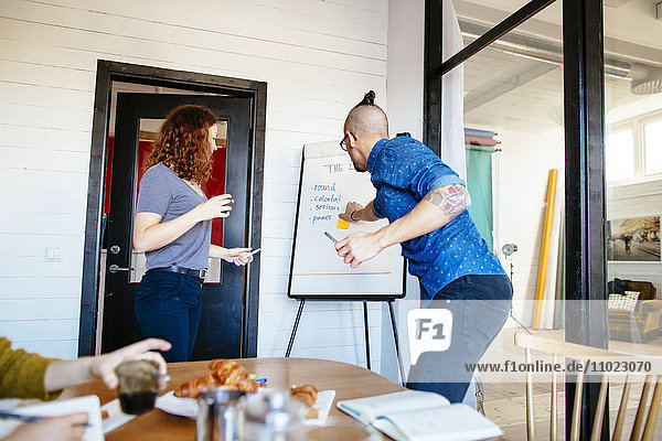 Business people having discussion over flipchart in board room