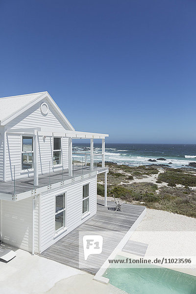 Weißes Strandhaus und Swimmingpool mit Blick auf das Meer unter sonnigem blauem Himmel