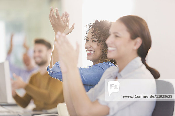 Businesswomen smiling and clapping in meeting