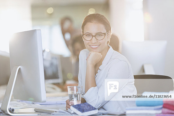 Portrait smiling businesswoman at computer in office