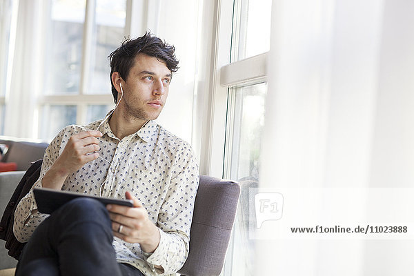 Businessman looking away while holding digital tablet in restaurant