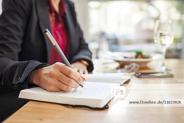 Midsection of businesswoman writing in book