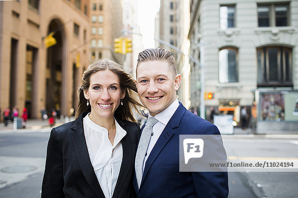Portrait of smiling businessman and woman standing on city street