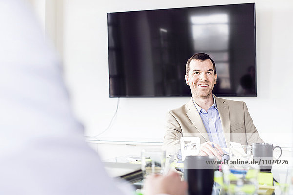 Smiling businessman sitting at conference table