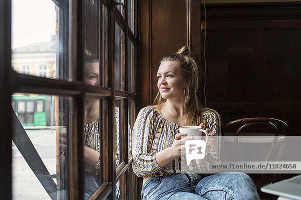 Thoughtful woman looking through window while sitting at cafe