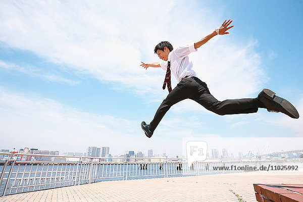 Young Japanese businessman jumping