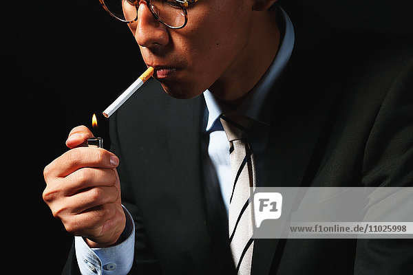 Junger japanischer Geschäftsmann raucht Zigarette