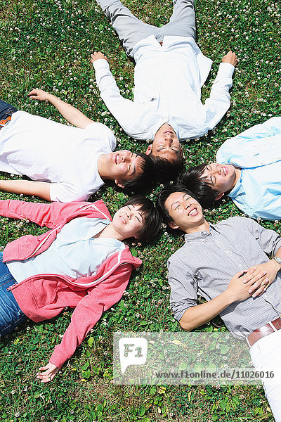 Gruppe junger japanischer Freunde  die im Gras liegen