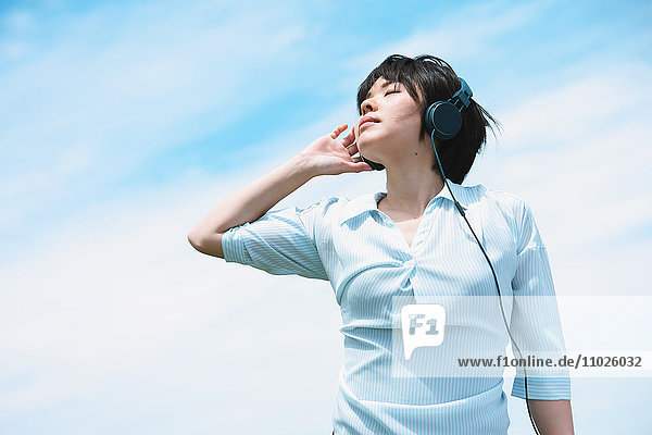 Junge japanische Frau entspannt sich unter dem blauen Himmel