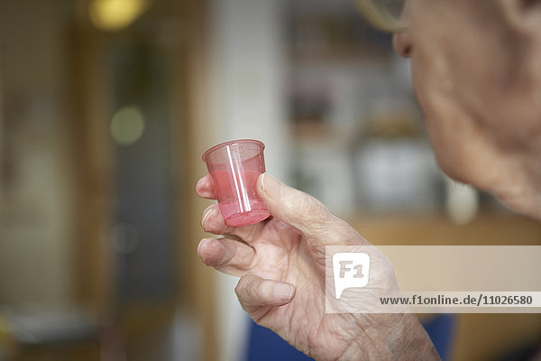 Senior nimmt Medikament in Seniorenheim
