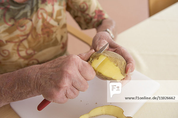 Seniorin schält Kartoffeln im Seniorenheim