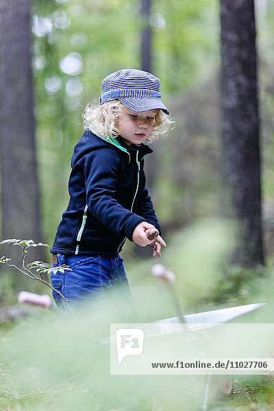 Junge im Wald mit Schubkarre