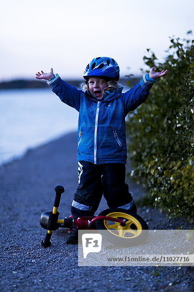 Glücklicher Junge mit Dreirad in der Abenddämmerung