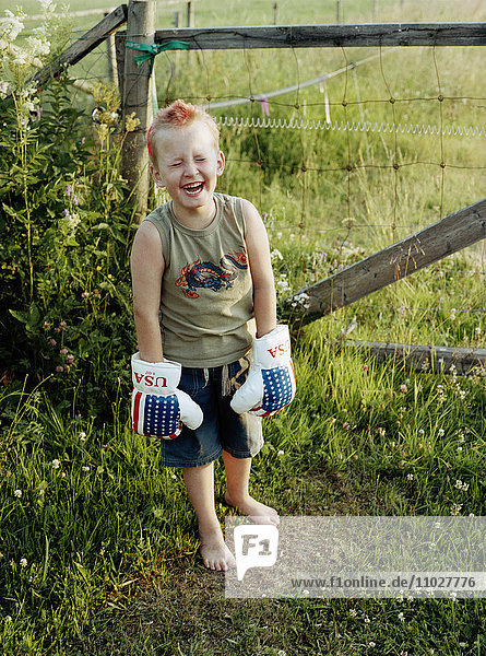 Ein lachender Junge mit Boxhandschuhen.