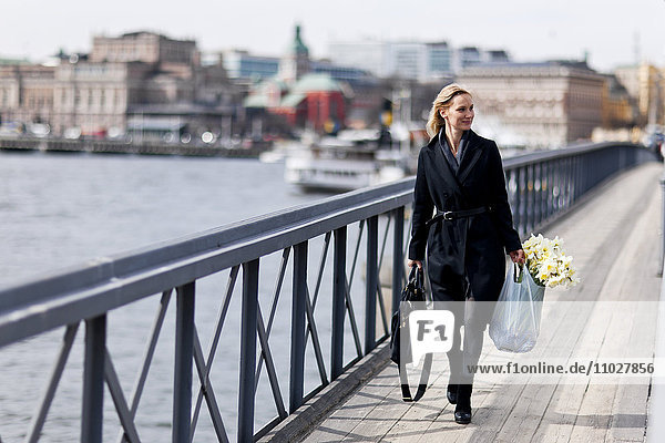 Woman walking with daffodils in shopping bag