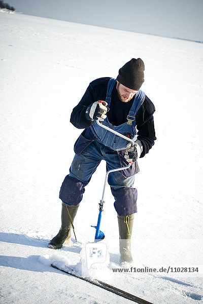 Arbeiter bohrt Loch in Eis