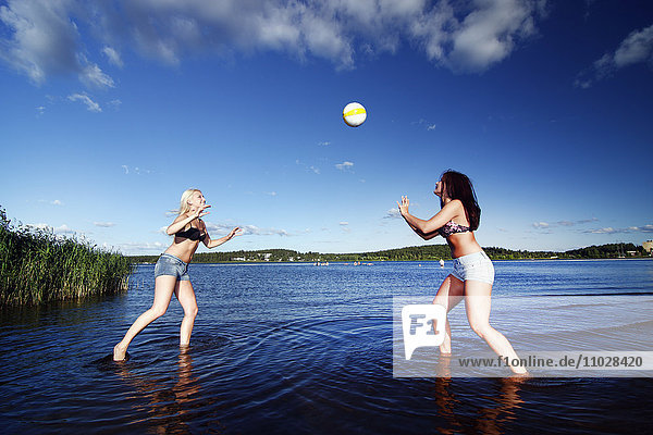 Frauen spielen Volleyball am Wasser