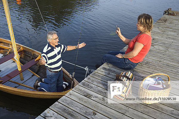 A woman photographing a man in a boat.