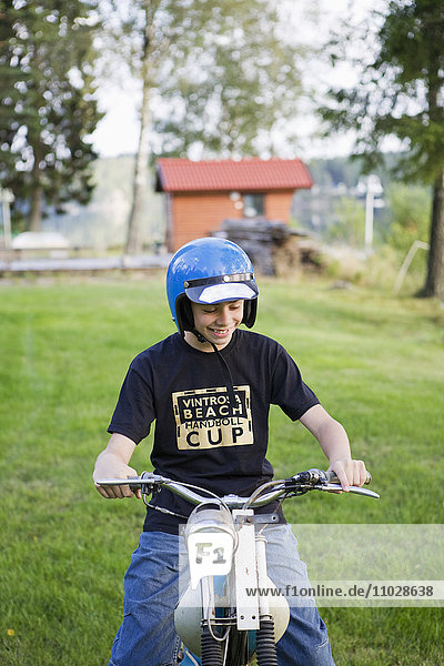 Sweden  Gothenburg  teenage boy (14-15) riding moped on lawn