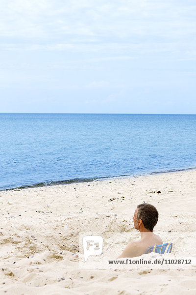 Mann entspannt sich im Sand am Strand