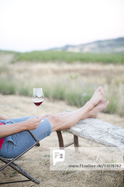Mid adult man relaxing with wine  low section