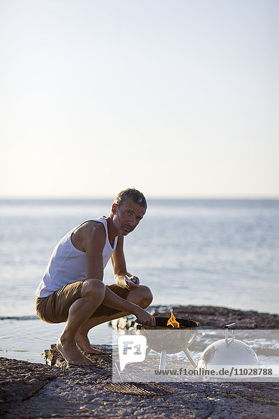 Mann bereitet Grillparty am Strand vor