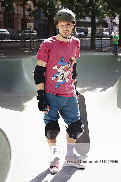 Mid adult man standing with skateboard