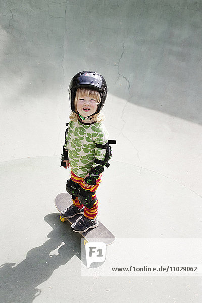 Portrait of boy standing on skateboard and looking at camera
