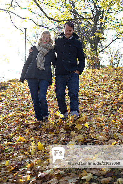 Ein Paar bei einem Spaziergang zwischen Herbstblättern.