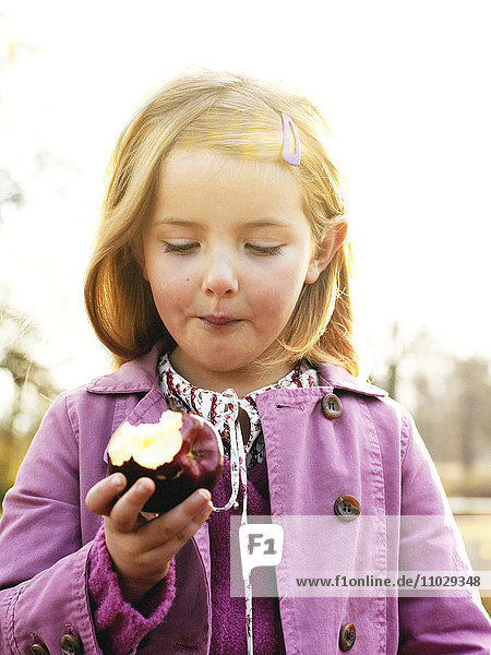 Mädchen isst Apfel im Freien.