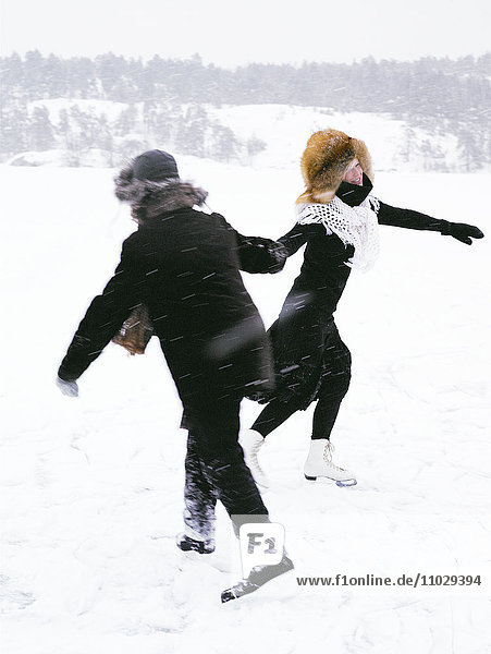 A man and a woman skating holding hands.