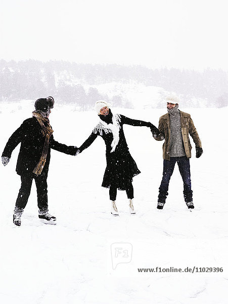 Three people skating  holding hands.