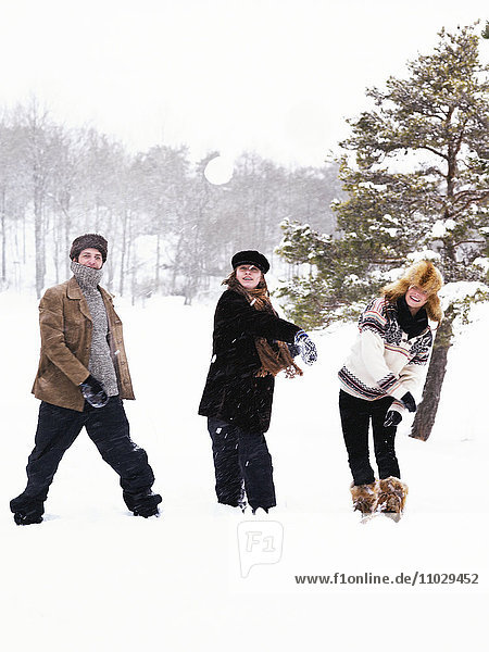 Three people in a snowball fight.