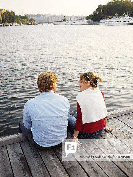 Ein Paar sitzt auf einer Promenade.
