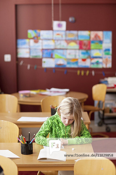 Schulmädchen zeichnet im Klassenzimmer