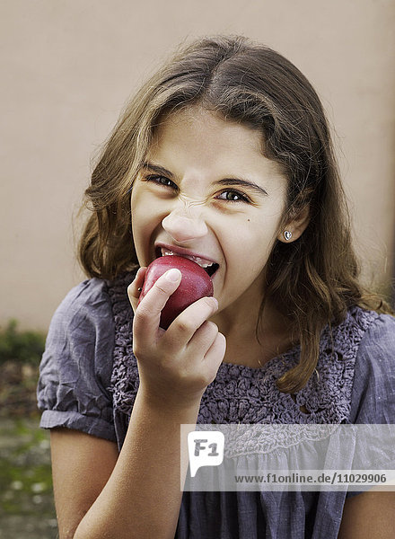 Ein Mädchen hält einen roten Apfel.