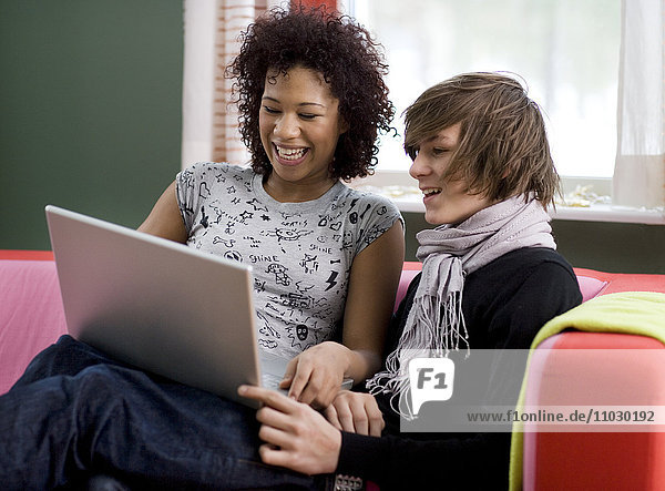 Teenager-Mädchen und Junge schauen auf Laptop