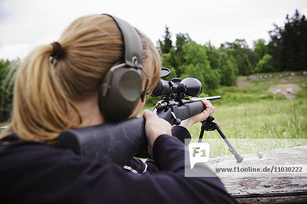 Woman target shooting in meadow