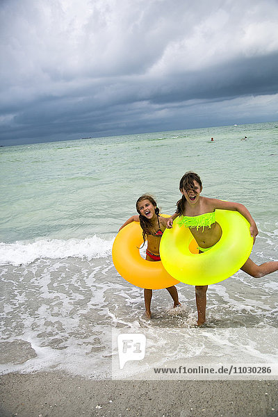 Happy girls with inflatable rings on beach