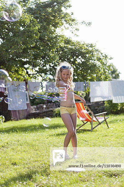 Girl making bubbles in garden
