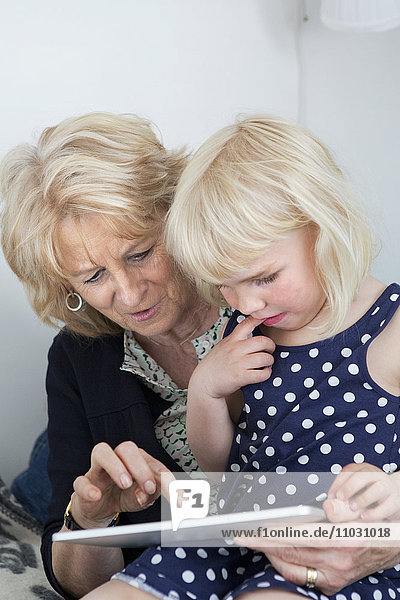 Großmutter mit Enkelin  die ein digitales Tablet benutzt