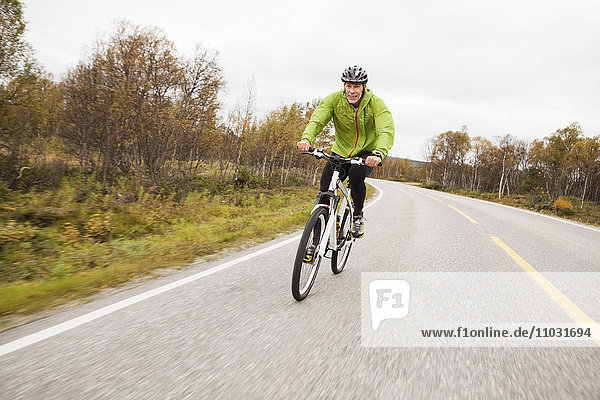Mature man setting riding mountain bike along country road