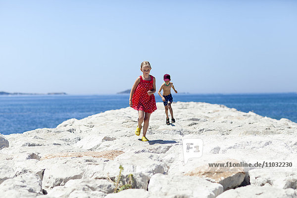 Junge und Mädchen laufen auf einem Steinpfeiler