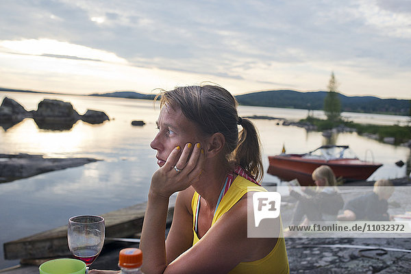 Frau sitzt am See  Kinder im Hintergrund  Siljan  Dalarna  Schweden